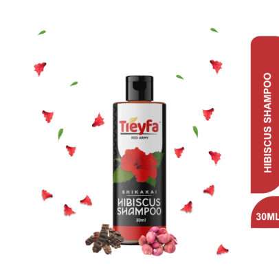 Small bottle of Treyfa Hibiscus Shampoo (30ml) next to fresh red hibiscus flowers.