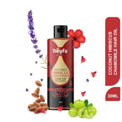 Small bottle of Coconut Hibiscus Hair Oil (30ml) next to hibiscus flowers and a coconut piece.